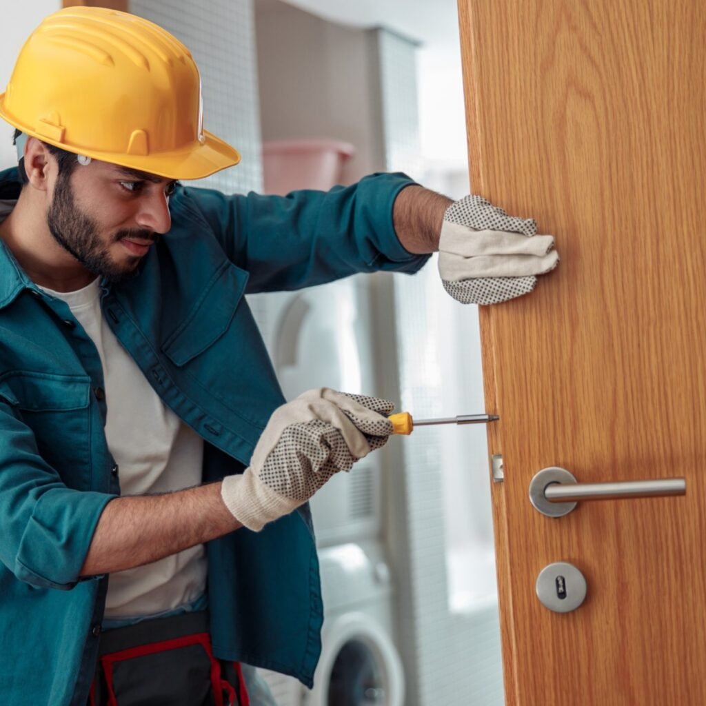 locksmith workman in uniform installing door knob hm5j