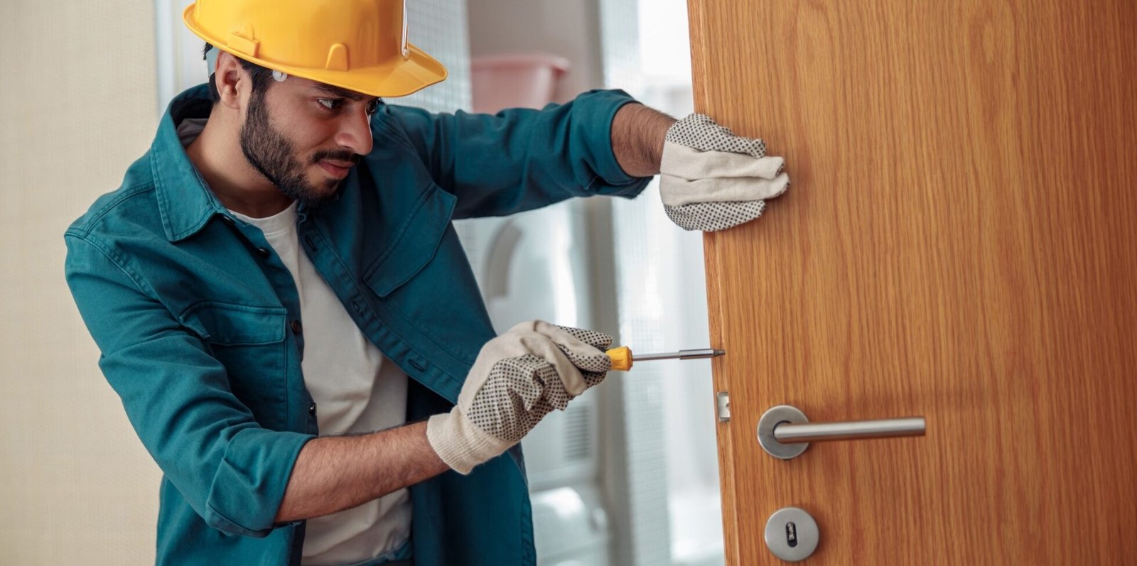 locksmith workman in uniform installing door knob hm5j
