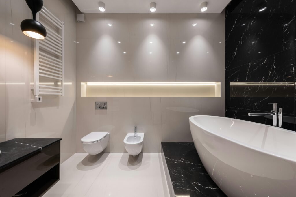 Sleek contemporary bathroom featuring a freestanding tub, black marble, and stylish lighting.